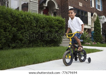 Young boy riding his first bicycle with training wheels (horizontal)