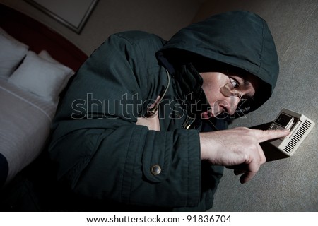 Freezing man adjusting thermostat