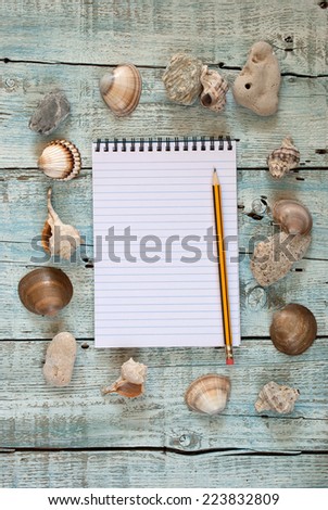 Sea shells and notebook on old wooden table