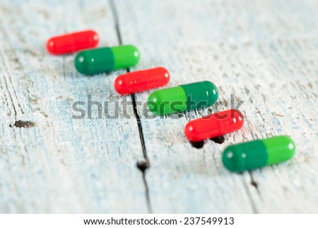 Green and red pills on old wooden table