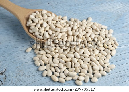Wooden spoon with white beans on old table