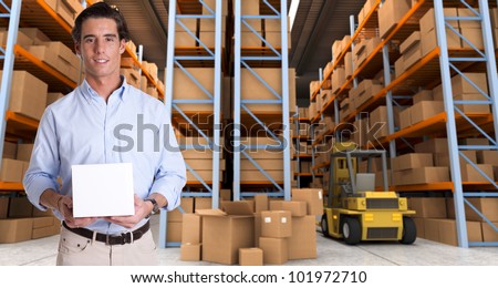 Young man holding a blank white box in a distribution warehouse