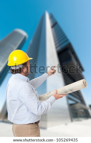 Man with helmet and blueprint and an old Parisian building