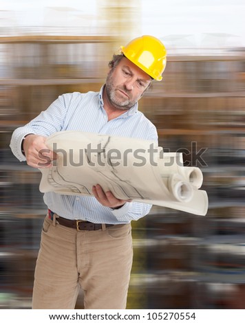 Man with helmet and blueprints and a blurry background