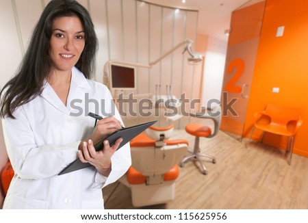 Friendly dentist filling a form at the dental cabinet