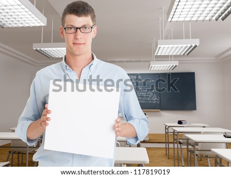 Young man holding a blank board in a classroom