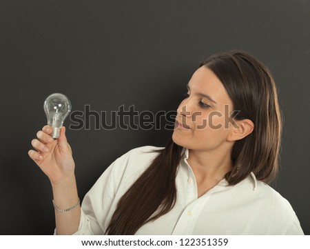 Woman holding a light bulb with a doubtful expression