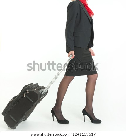 Air hostess on the move carrying a trolley suitcase