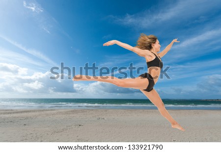Young woman flying in a graceful jump at the beach