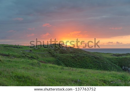Sunset with green hills and calm ocean