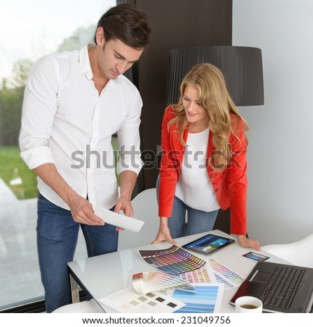 Man and woman in an office surrounded by color charts, material samples and technology