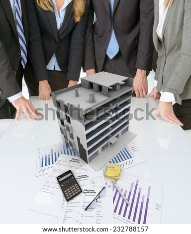 Meeting with people around a table with an architectural model on top of documents and charts