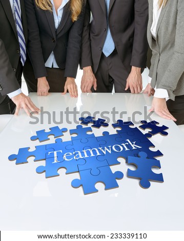 Meeting with people around a table with a puzzle with the word teamwork