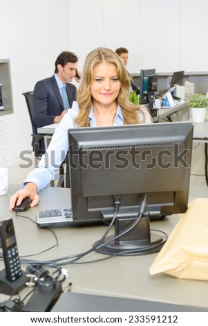 Woman working at her desk, with people working at the background