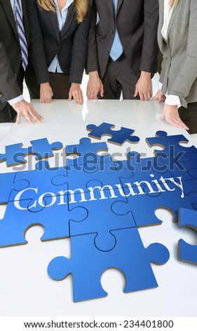 Meeting with people around a table with a puzzle with the word community