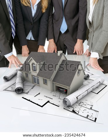 Meeting with people around a table with an architectural model on top of documents and charts