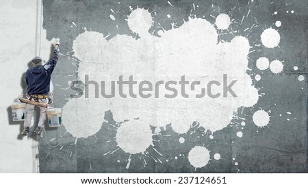 Building Painter hanging from harness painting a wall with splatters ideal for inserting your own message