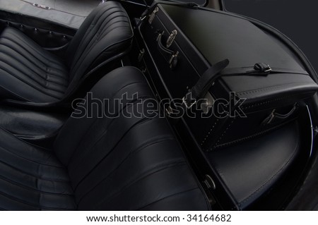 Backseat of a vintage car with retro luggage in the trunk