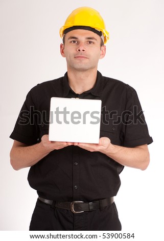Man in black wearing a yellow safety helmet holding a white box