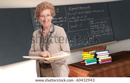 stock photo Friendly mature teacher pointing to a book in a classroom