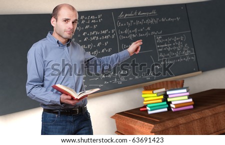 Young male teacher pointing to the blackboard in a maths classroom