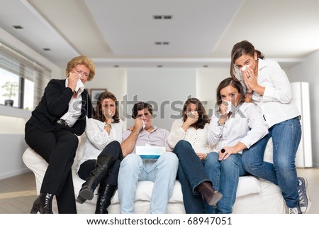 A group of family members sitting at home crying watching tv