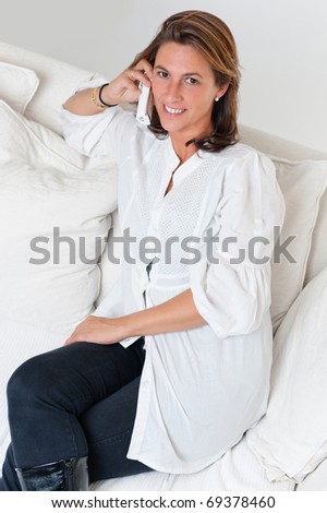 Relaxed woman sitting on a sofa having a telephone conversation