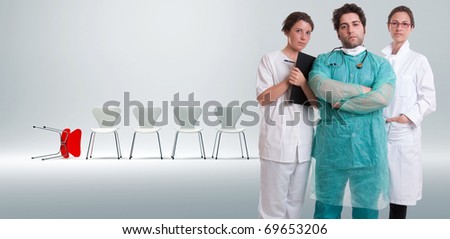 Serious medical staff with a row of white chairs an a fallen red one on the background