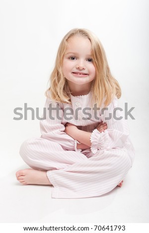 Cute little blonde girl in her pajamas sitting on the floor - stock