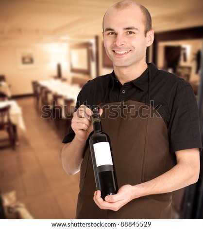 Smiling sommelier presenting a wine bottle with a blank label in a restaurant