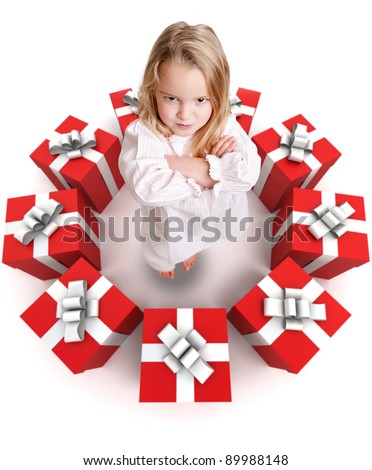 Sulking funny little girl in pajamas surrounded by a ring of presents