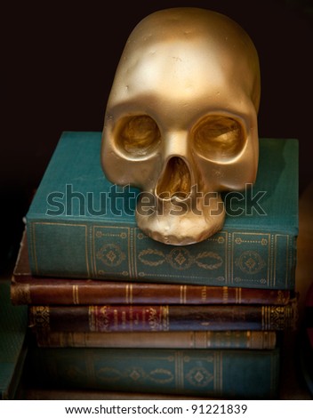 Golden skull on top of a pile of old books