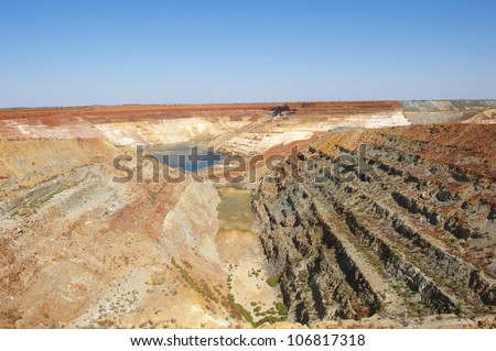 Man made deep hole for open cut mining in outback Australia, close to Meekatharra in Western Australia, panoramic view with copy space.