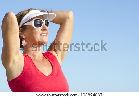 Portrait of happy attractive looking middle aged woman joyful laughing, isolated with sunshine on face and sky as background and copy space.