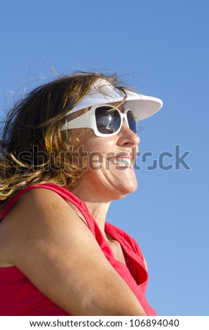 Portrait of happy attractive looking middle aged woman joyful laughing, isolated with sunshine on face, sky as background and copy space.