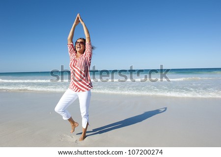 Attractive looking mature woman, happy doing exercises at beach, isolated with ocean and blue sky as background and copy space.