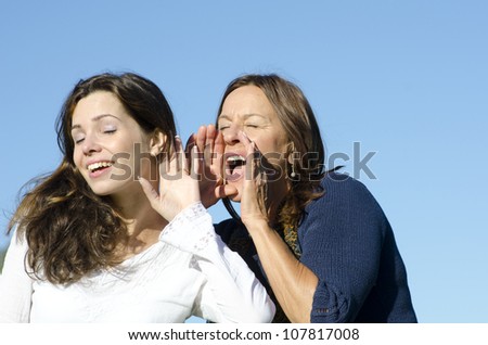 Communication between two women, between two generations, mother and daughter, two friends, one shouting, one listening, with clear blue sky as background and copy space.