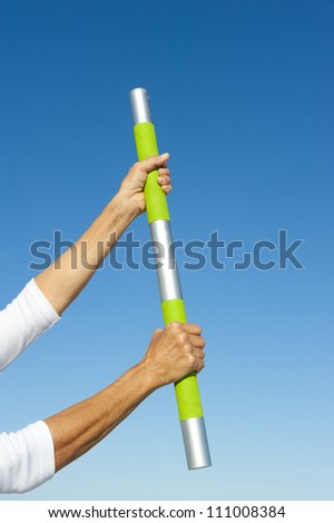 Arms with hand gripped around weight, isolated with blue sky as background and copy space.