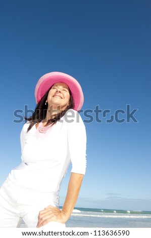 Sexy retired senior woman relaxed holiday, isolated with ocean and blue sky as background and copy space.