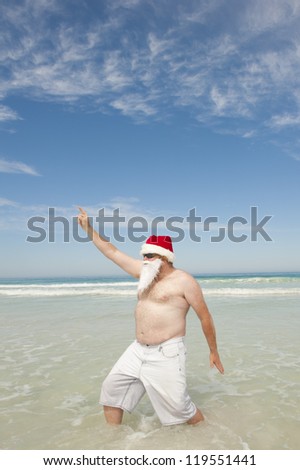 Relaxed and cool Santa Claus enjoying tropical holiday vacation at beach, isolated with ocean and blue sky as background and copy space.