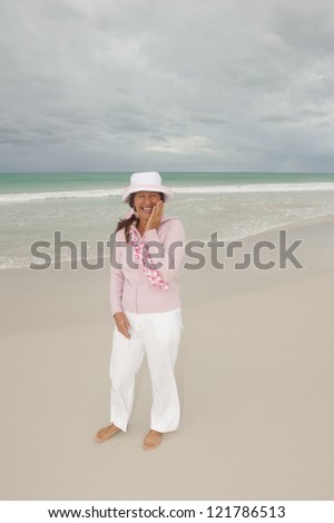 Attractive, friendly and confident looking middle aged woman at beach enjoying active retirement holiday, isolated with storm clouds in the sky and ocean as background and copy space.