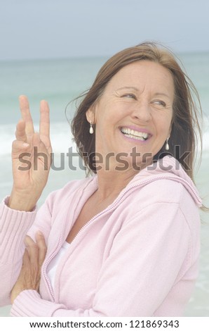 Portrait attractive middle aged woman enjoying active retirement, happy smiling, isolated with ocean as blurred background.