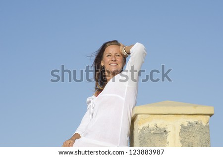Portrait Attractive happy middle aged woman posing relaxed outdoor, enjoying active retirement, isolated with blue sky as background and copy space.