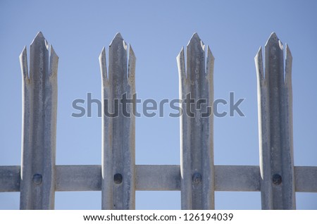 close up of tips of galvanized steel safety fence isolated with blue sky as background and copy-space