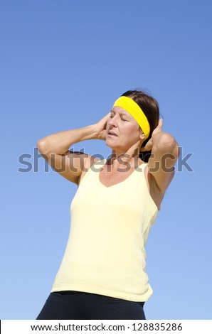 Portrait attractive mature woman, concentrated, exhausted exercising, keeping fit and healthy with active retirement, isolated with blue sky as background and copy space.