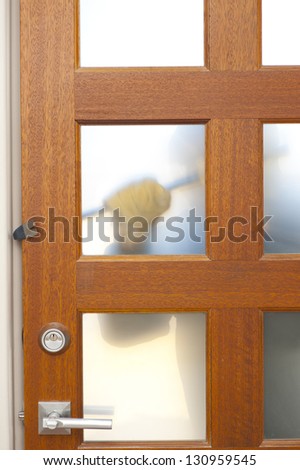 Burglar, thief  with gloves, holding crowbar trying to break in home, unlock door, blurred visible silhouette behind milky windows, with copy space.