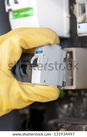 Hand with protecting safety gloves of electrician at electric meter or switch board at house exchanging fuse.