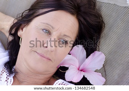 Portrait beautiful mature woman  with sad and lonely facial expression, lying alone and thoughtful with flower on hammock.