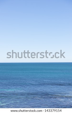 Lookout over open ocean sea with horizon and clear clean blue sky as backdrop.