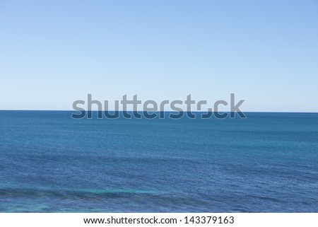 Panoramic view over open ocean sea with horizon and clear clean blue sky as backdrop.